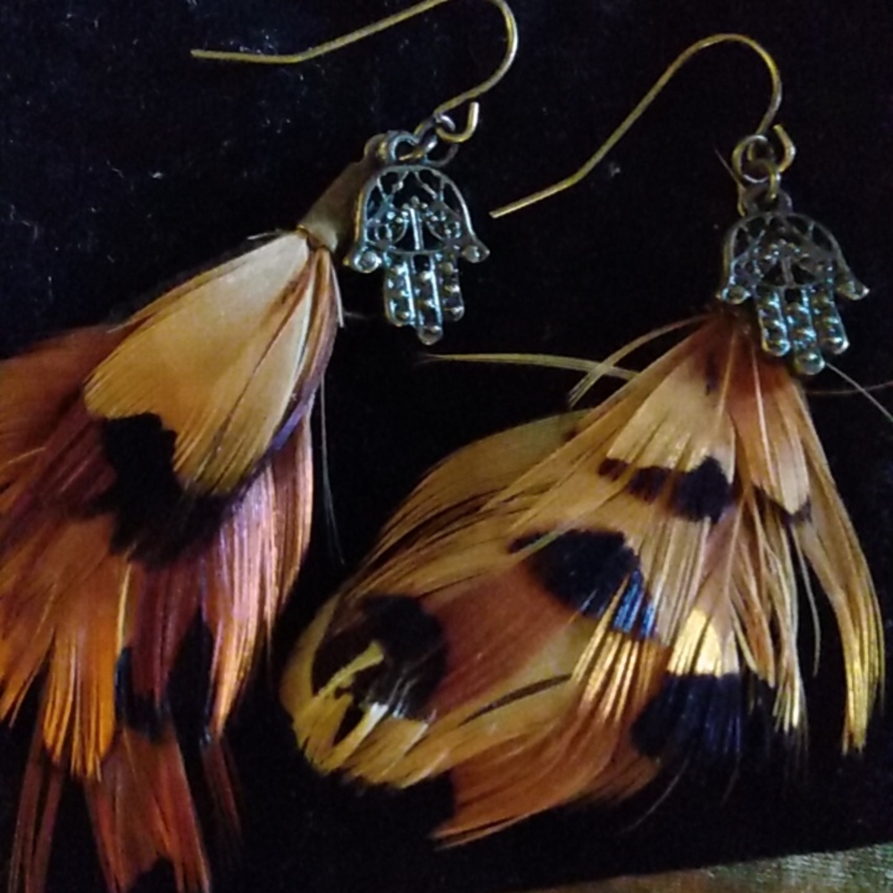 Feather earrings with Hamsa hand charm meant to protect from evil eye